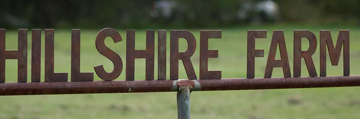 Hillshire farm rusted metal sign in front of a green pasture